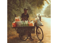 暑期的8月早上的三界镇街头吃包子，一辆卖西瓜的三轮车停在马路边，老伯正在称西瓜。